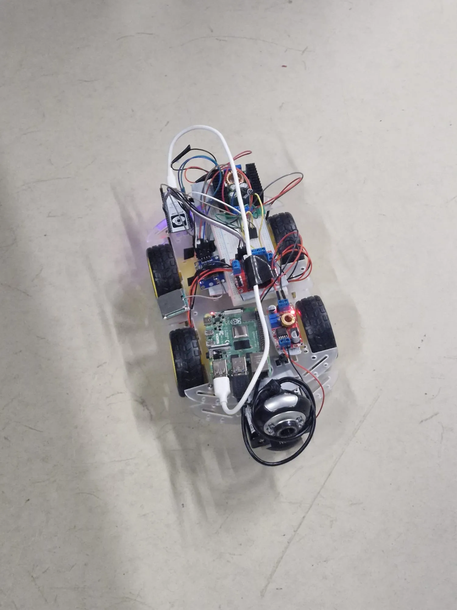 Top-down view of the four-wheel rover showing the Raspberry Pi, motor driver, buck converters and camera